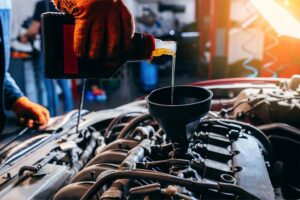 mechanic pouring new oil into a vehicle